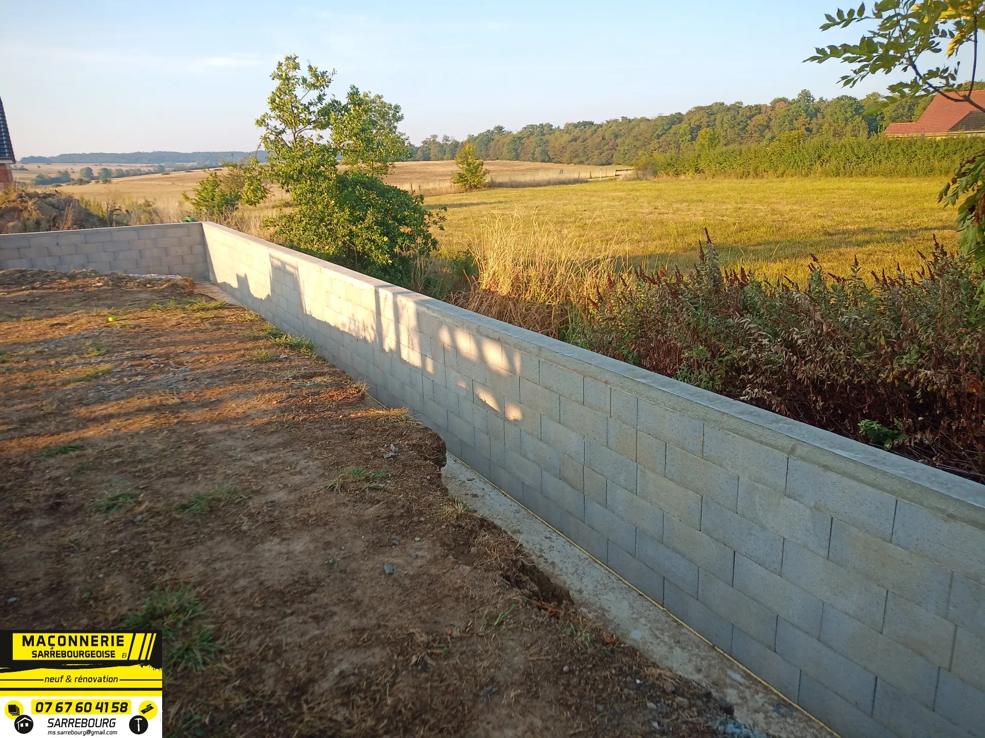 Long mur de soutènement en agglo en bordure de champ