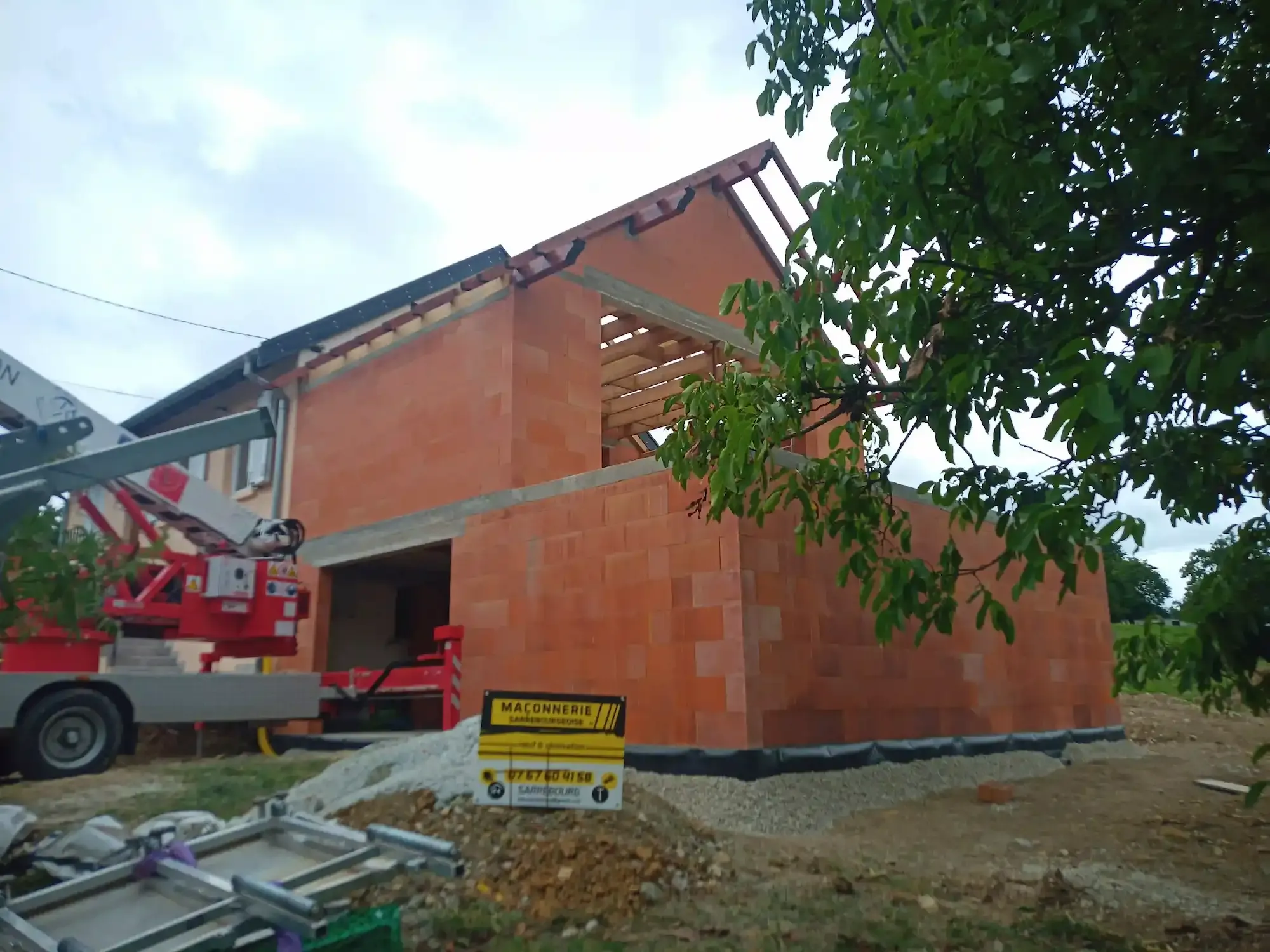 Extension de maison en briques en cours de construction, accolée à la maison existante